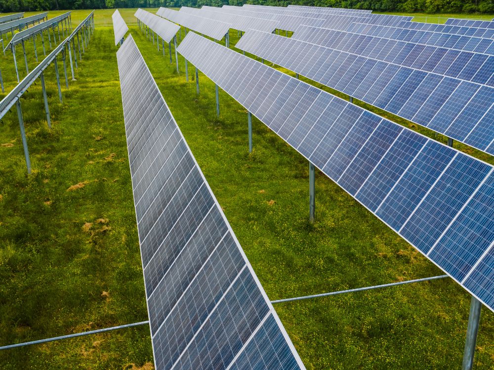 Estrutura com fileiras de painéis solares em área aberta, representando em larga escala o que é sistema híbrido de energia para geração contínua.