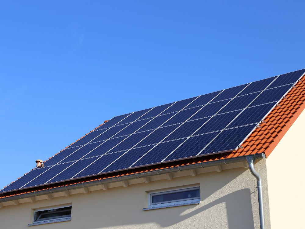Sistema solar híbrido instalado em telhado residencial com painéis fotovoltaicos conectados à rede e apoio por baterias para fornecimento contínuo.